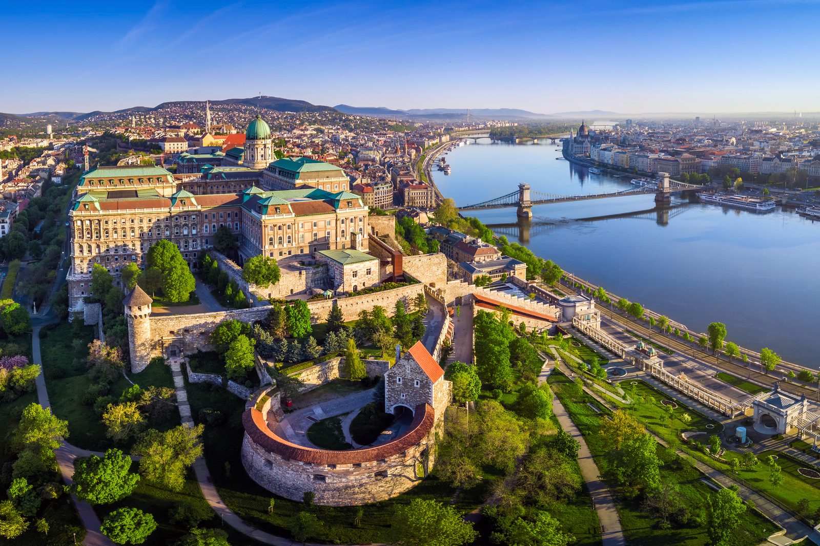 Fisherman’s Bastion at golden sunrise with Parliament beyond the Danube